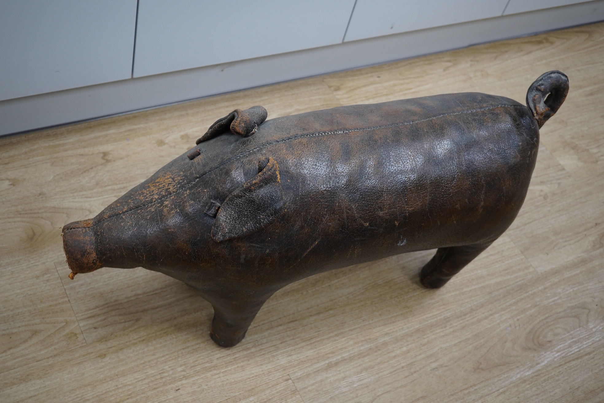 A Liberty brown leather pig foot stool, 90cm long. Condition - the end of the tail and snout are missing and generally leather scuffed